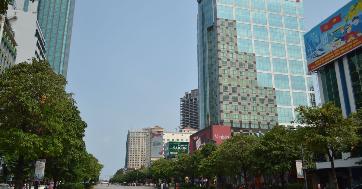 A vibrant daytime view of downtown Ho Chi Minh City featuring modern skyscrapers and lush greenery.