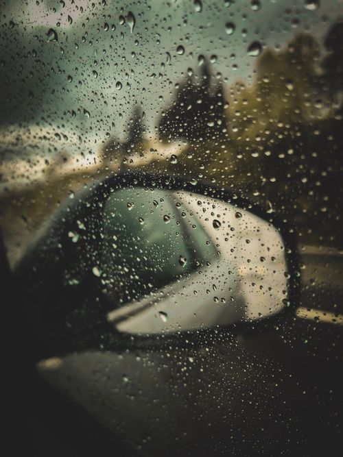 Free Through car window with raindrops of surveillance mirror during road trip in rainy countryside Stock Photo