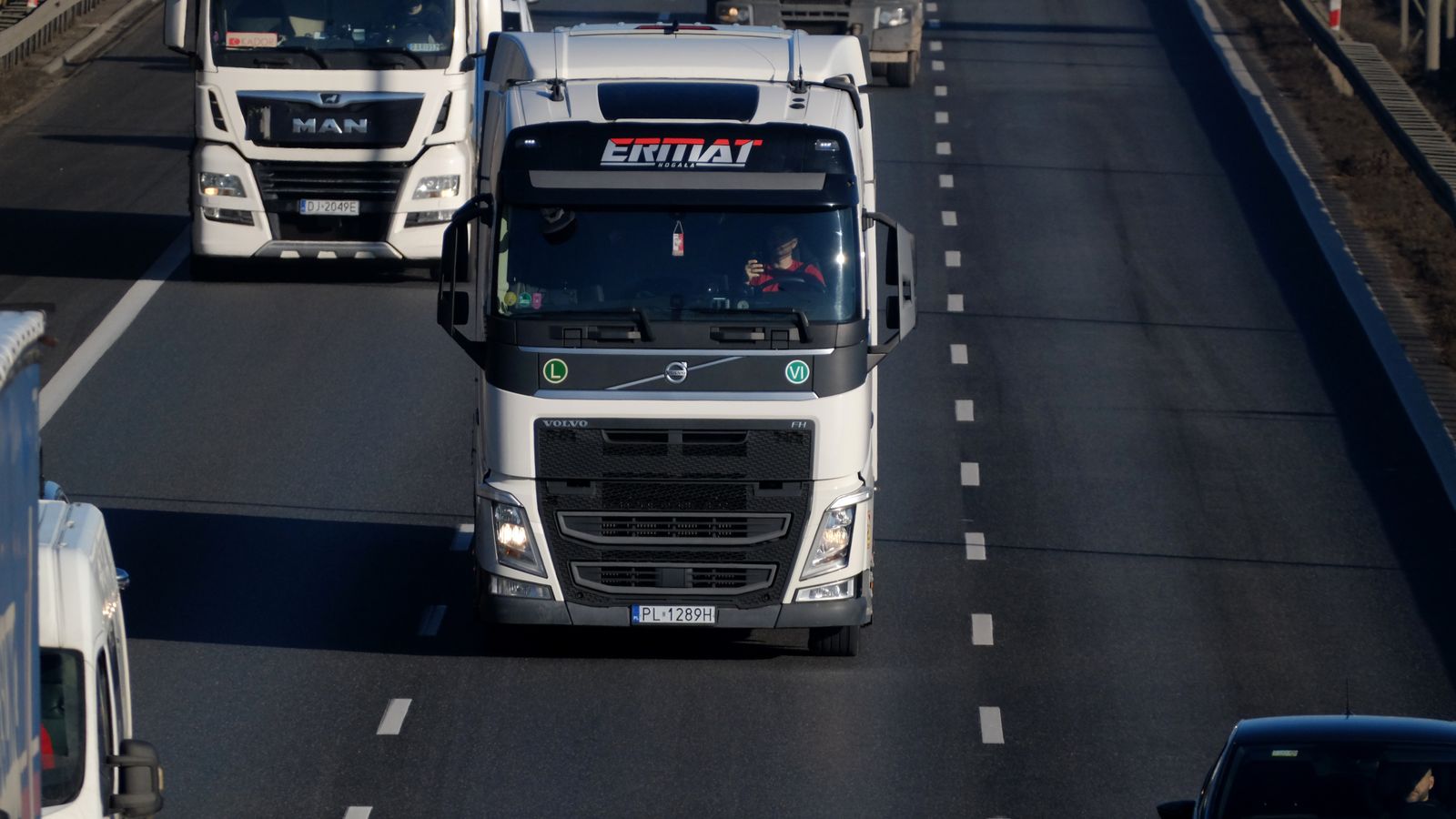 Heavy duty trucks driving on a highway, showcasing transportation and logistics.