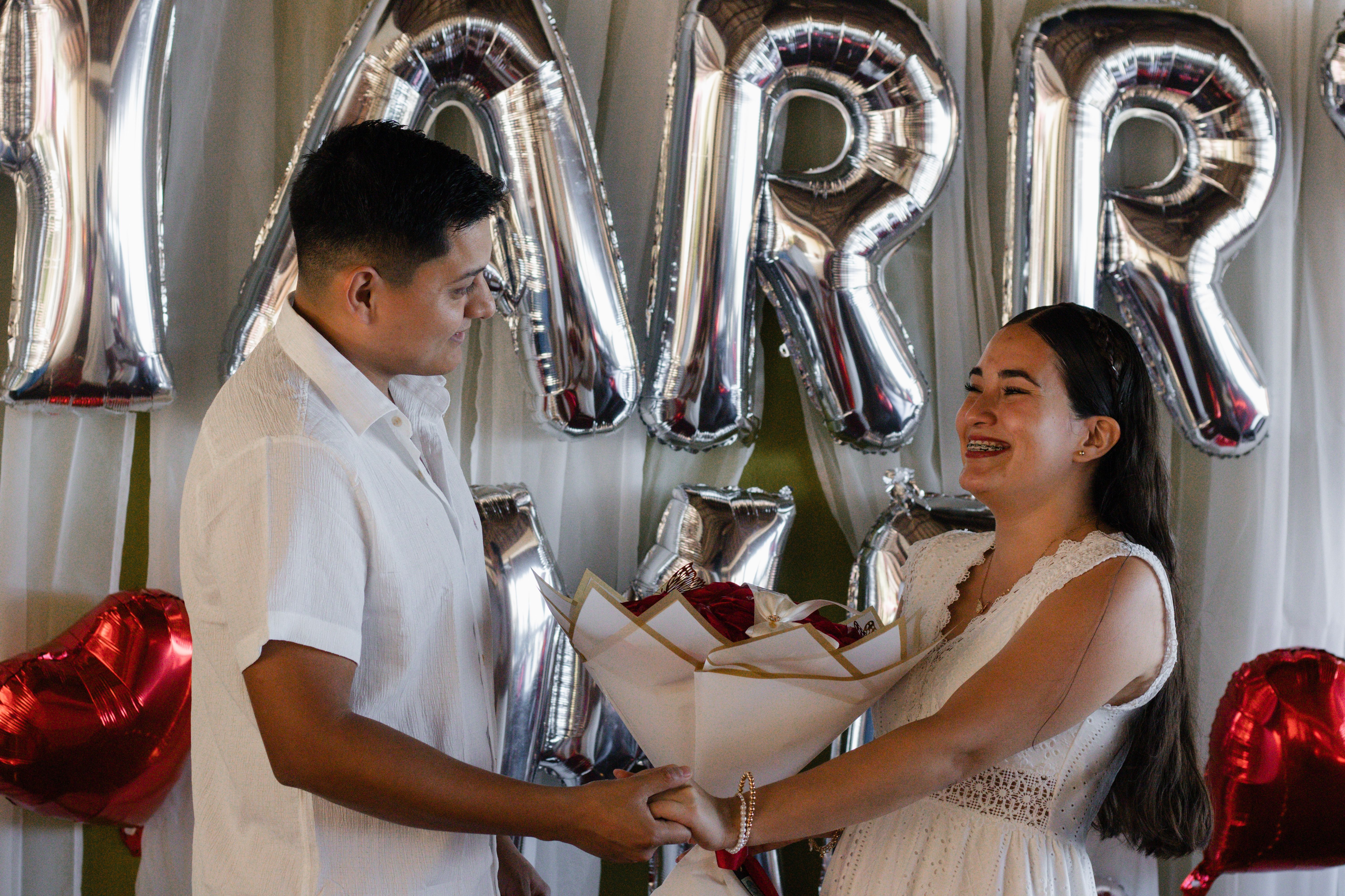 Couple celebrating their engagement with balloons and a bouquet