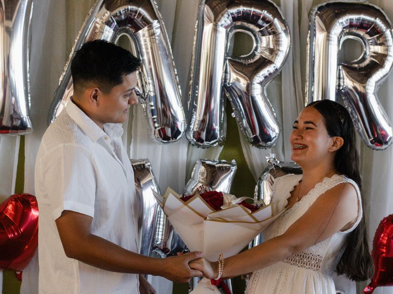 Couple celebrating their engagement with balloons and a bouquet