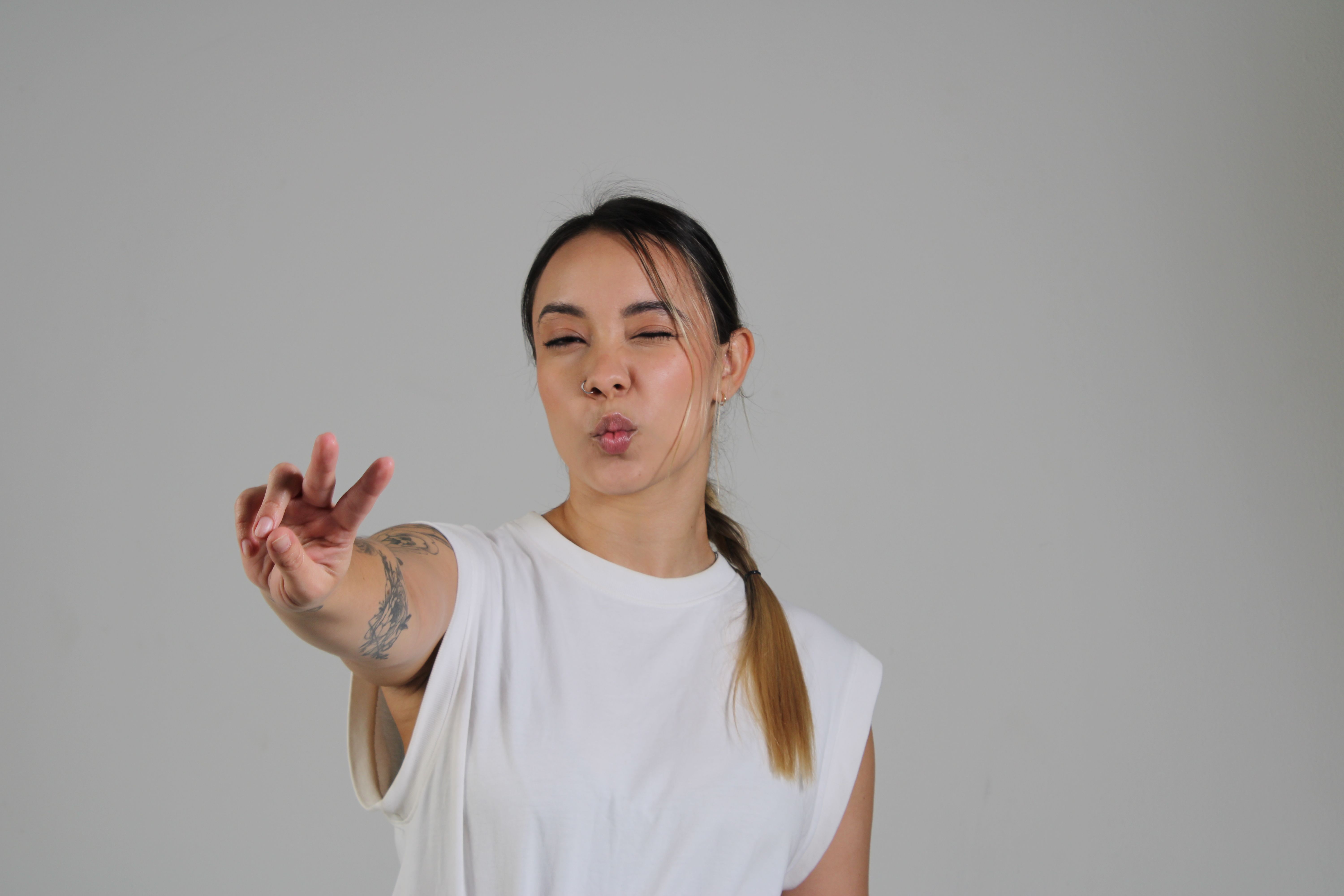 Playful Woman Making Peace Sign Gesture Indoors · Free Stock Photo