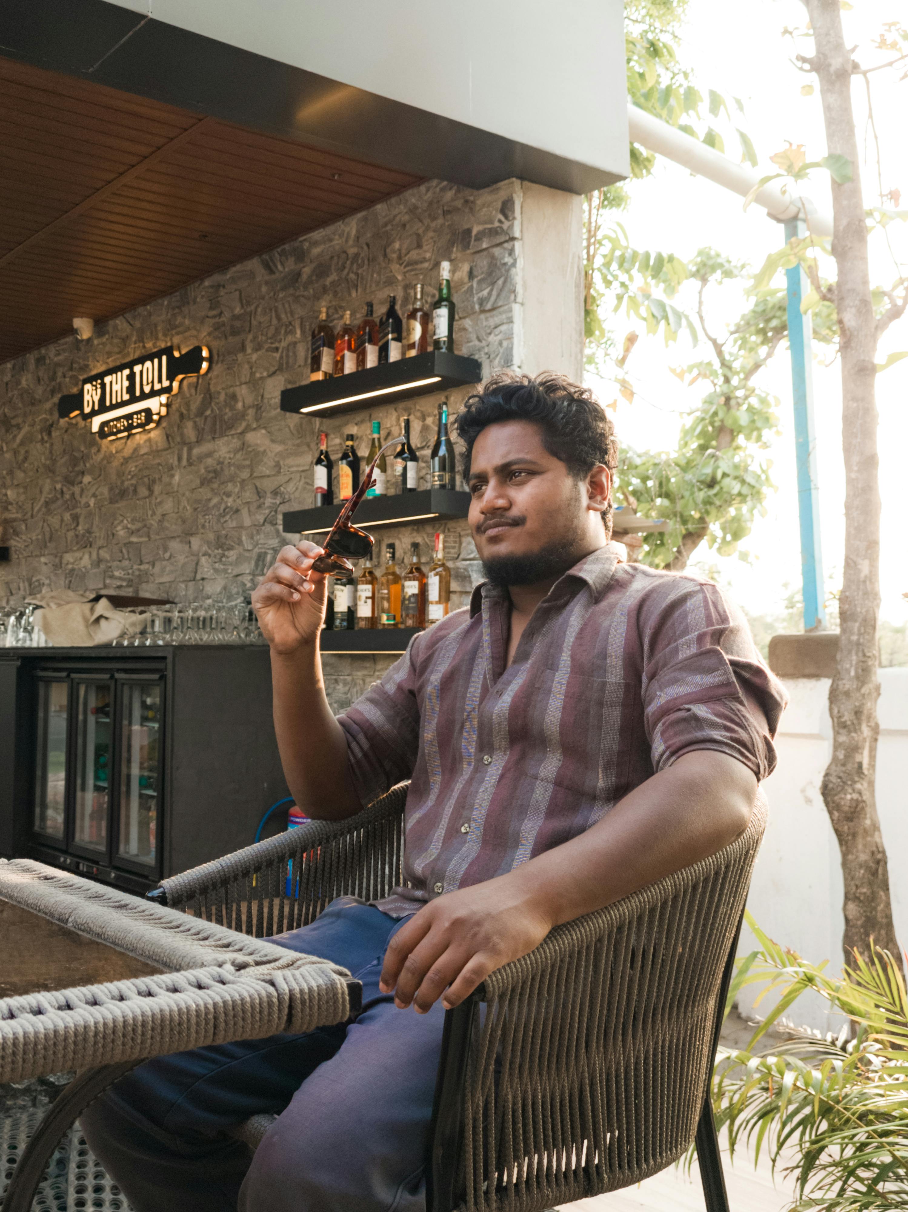 A man enjoys a drink at an outdoor bar on a sunny day.