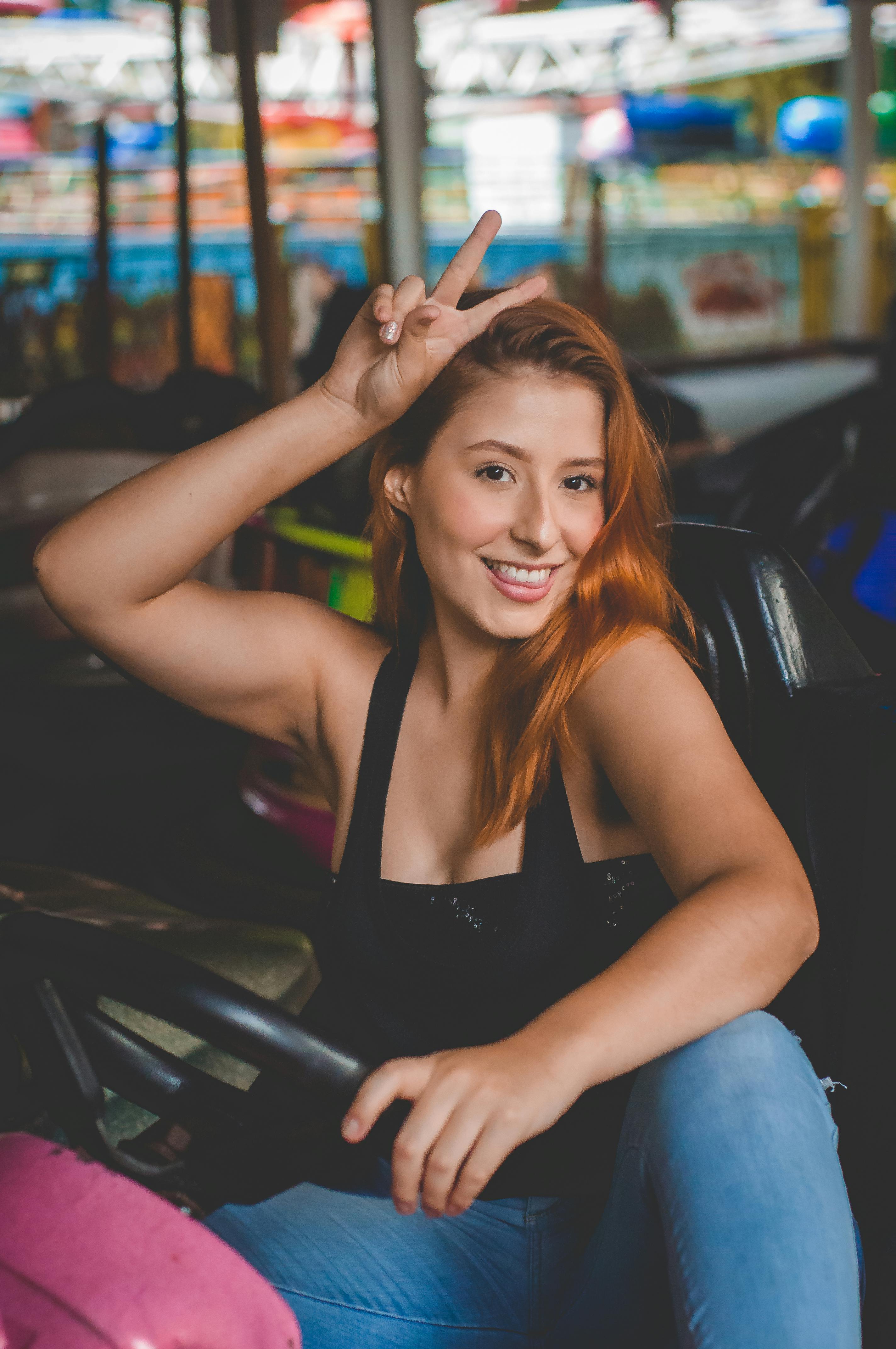 cheerful woman sitting in bumper car and showing peace sign