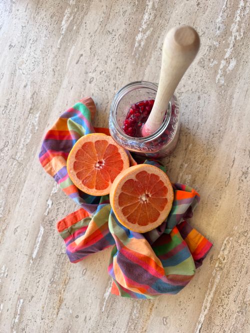 Free Colorful flat lay of sliced grapefruit on a rainbow cloth with a mason jar of pomegranate seeds. Stock Photo