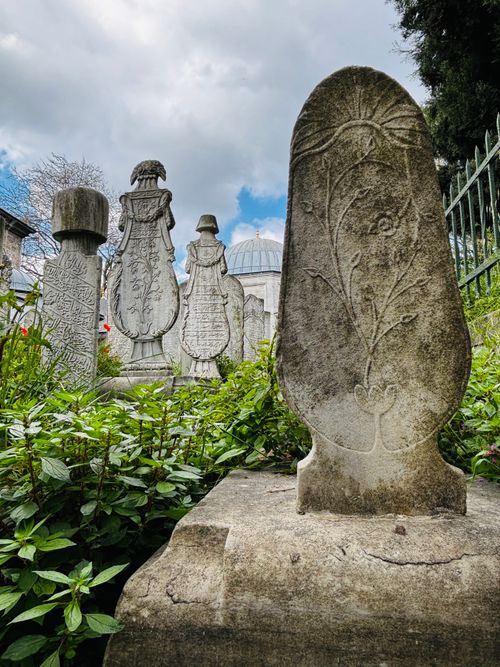 Free Ancient Ottoman tombstones with intricate carvings in Istanbul, surrounded by lush greenery and historical architecture. Stock Photo