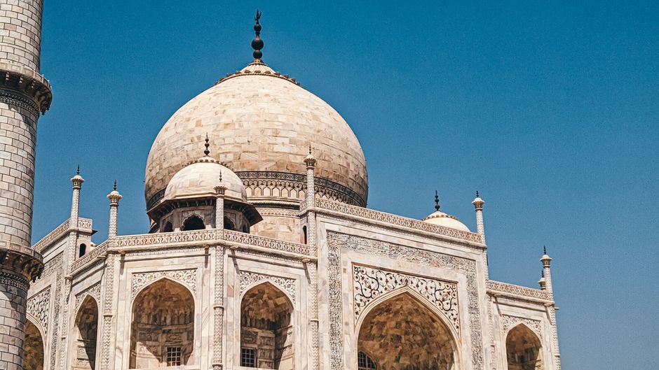 Captivating architectural detail of the Taj Mahal under a clear blue sky in Agra, Uttar Pradesh, India.