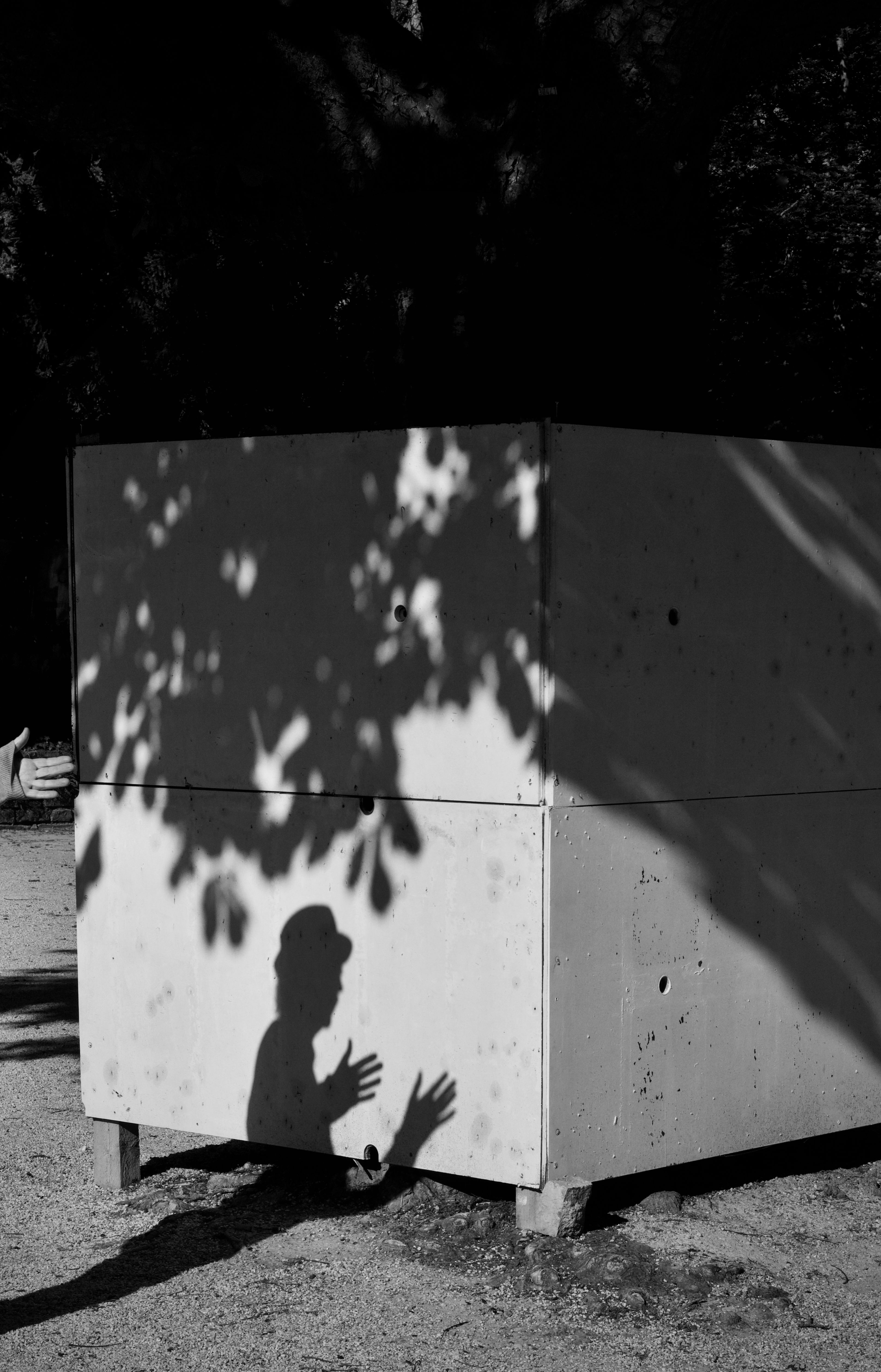 Shadow of a person cast on a large box outdoors, creating a mysterious scene.