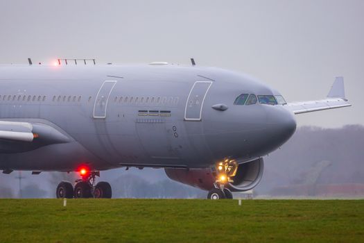 Close-up of a large commercial airplane on a runway during an overcast day.