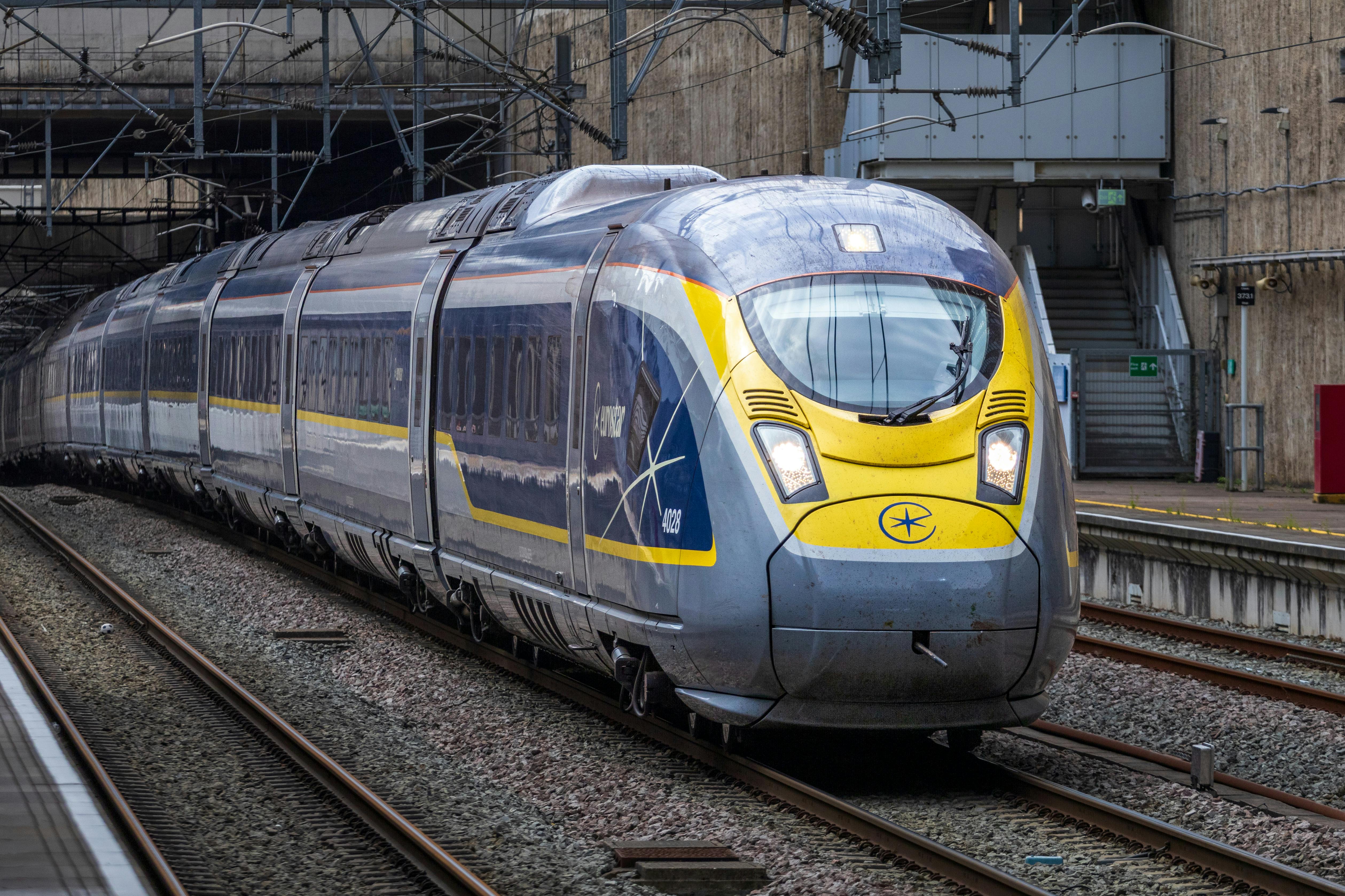 Modern high-speed passenger train traveling through a railway station.