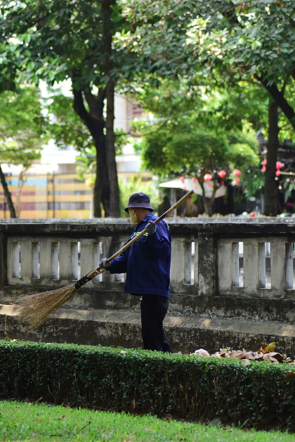 Gardener sweeping fallen leaves in a landscaped park