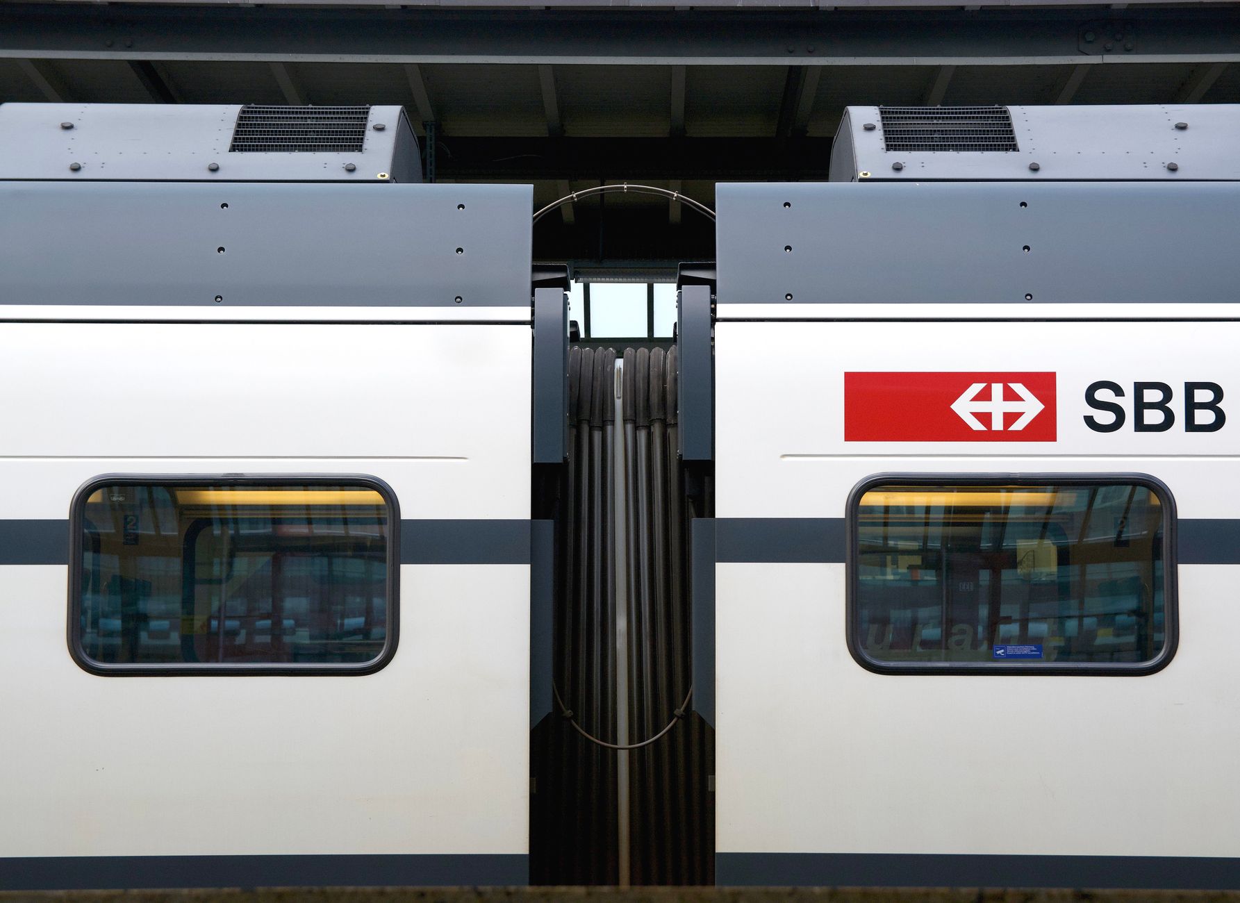 Close-up of an SBB train carriage window reflecting station interior in Switzerland.