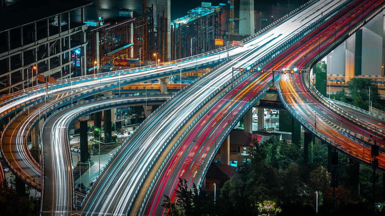 Free From above long exposure traffic on modern highway elevated above ground level surrounded by urban constructions in evening Stock Photo