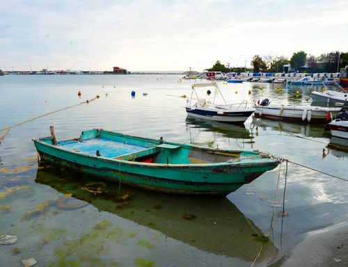 Free Peaceful image of a small harbor at dawn with anchored fishing boats and calm waters. Stock Photo