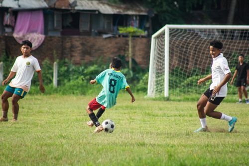 Free Boys playing soccer in a field, captured during a lively game in Myanmar. Stock Photo
