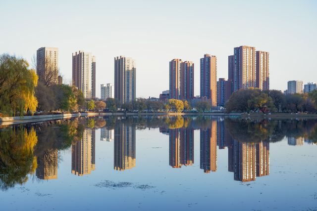 Stunning skyline of Shenyang reflected in a serene lake, capturing urban symmetry and autumn colors.