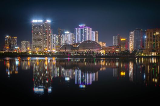 Captivating nighttime cityscape with vibrant lights reflecting on the water, highlighting modern architecture.