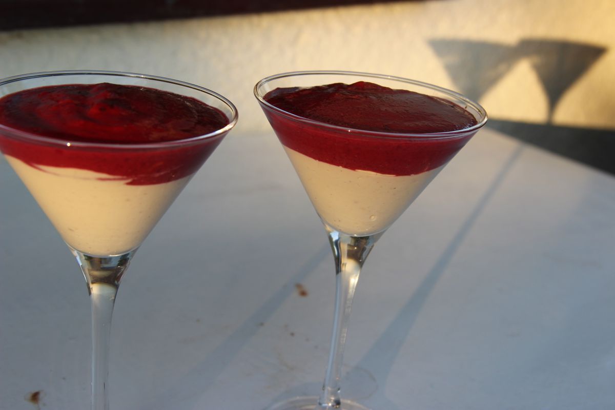 Two martini glasses filled with pale vanilla cream topped with a thick raspberry coulis layer