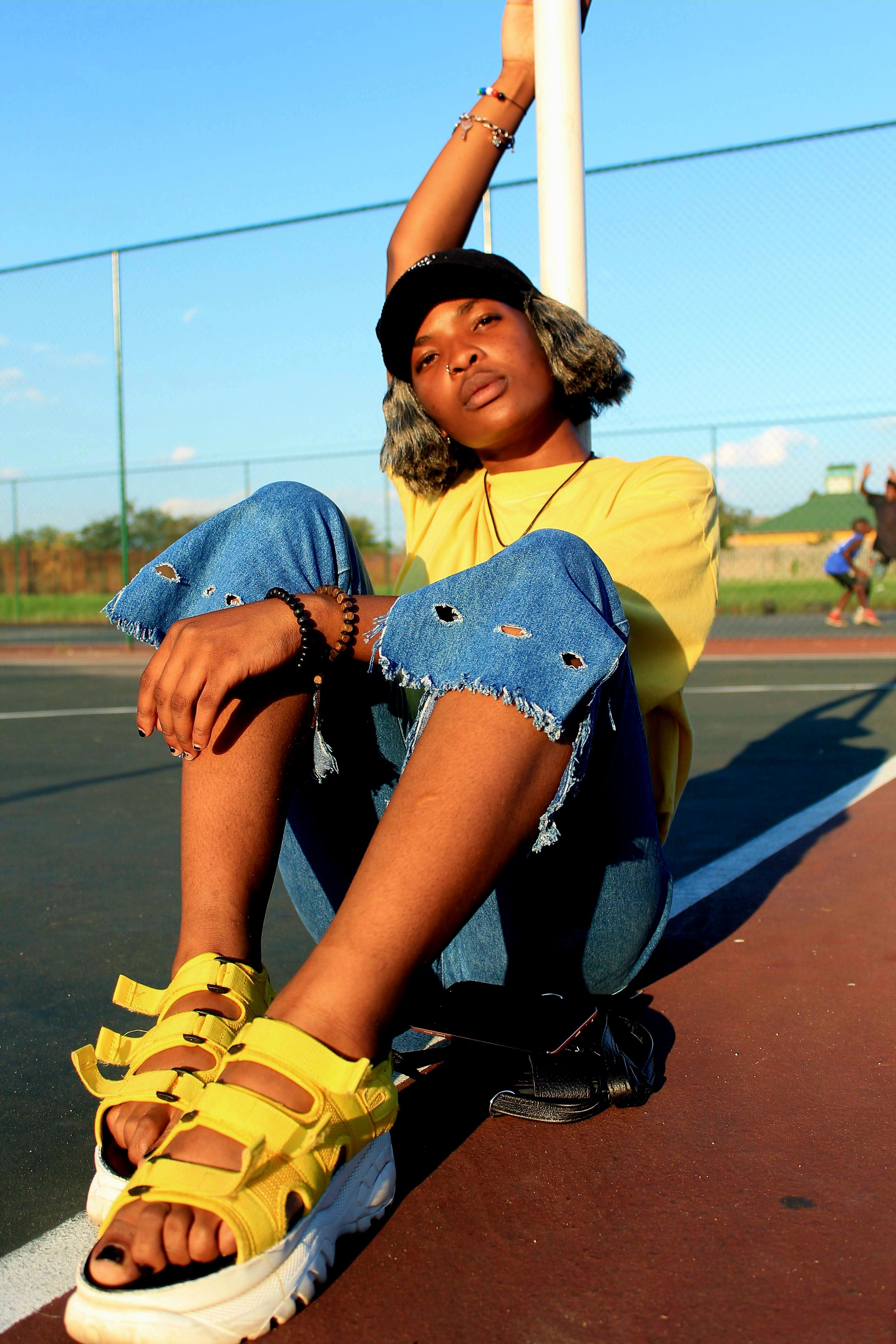 Jovem moderna sentada em uma quadra de basquete, vestindo roupas casuais de verão e exalando confiança.