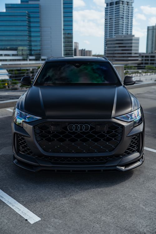 Free Sleek black luxury car parked in rooftop lot with city skyline view. Stock Photo