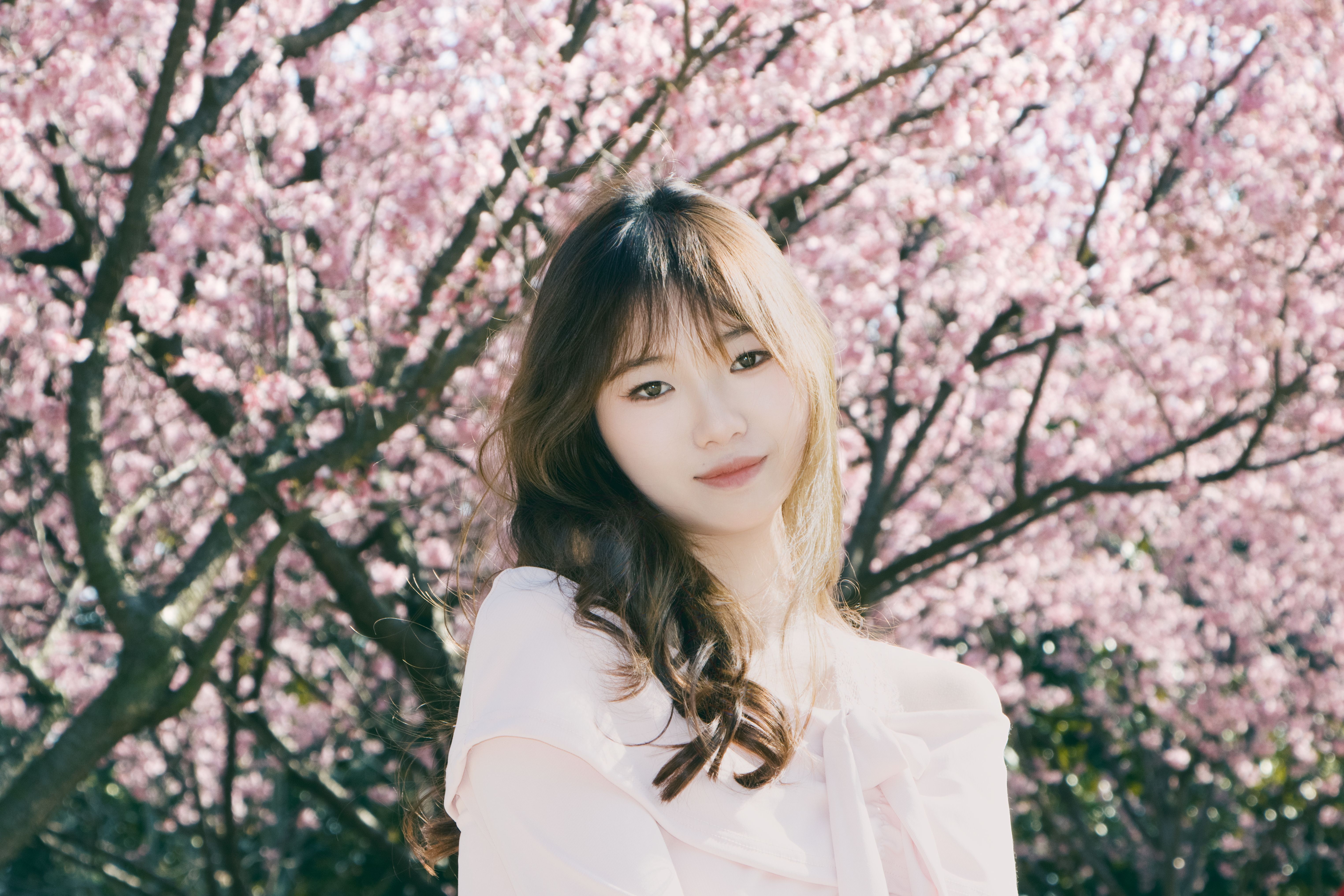 Portrait of a woman among blooming cherry blossoms on a spring day.