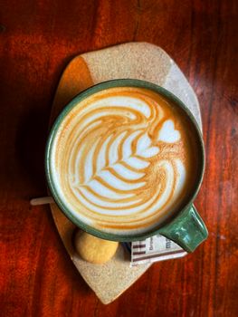 Aerial view of a beautifully designed latte art with heart shape, served with cookies in Hyderabad.