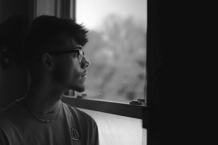 Man In Crew Neck T-shirt Wearing Black Framed Eyeglasses Looking Out The Window