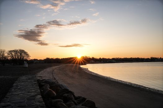 Capture of a serene beach at sunrise with a golden sky and tranquil water.