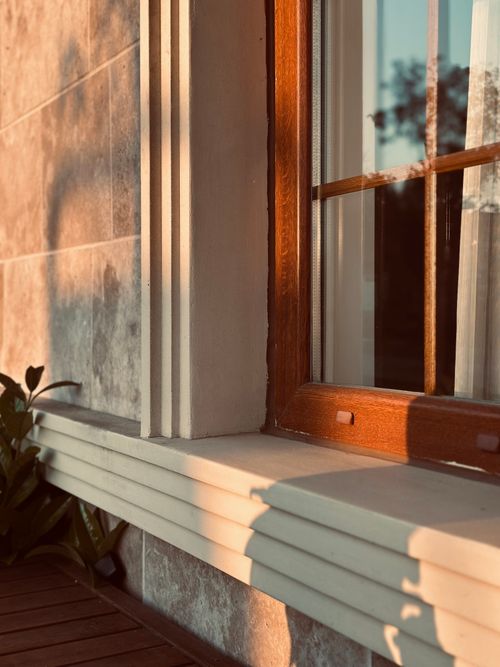 Free Close-up of a sunlit window frame highlighting architectural details and warm wood tones. Stock Photo