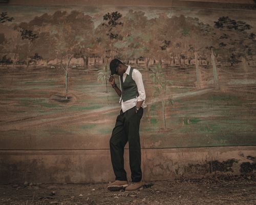 Free Artistic photograph of a stylish man posing in front of a detailed wall mural outdoors. Stock Photo