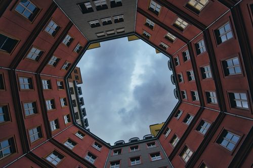 Free Dramatic upward view of an architectural courtyard in Berlin showcasing geometric symmetry against a cloudy sky. Stock Photo