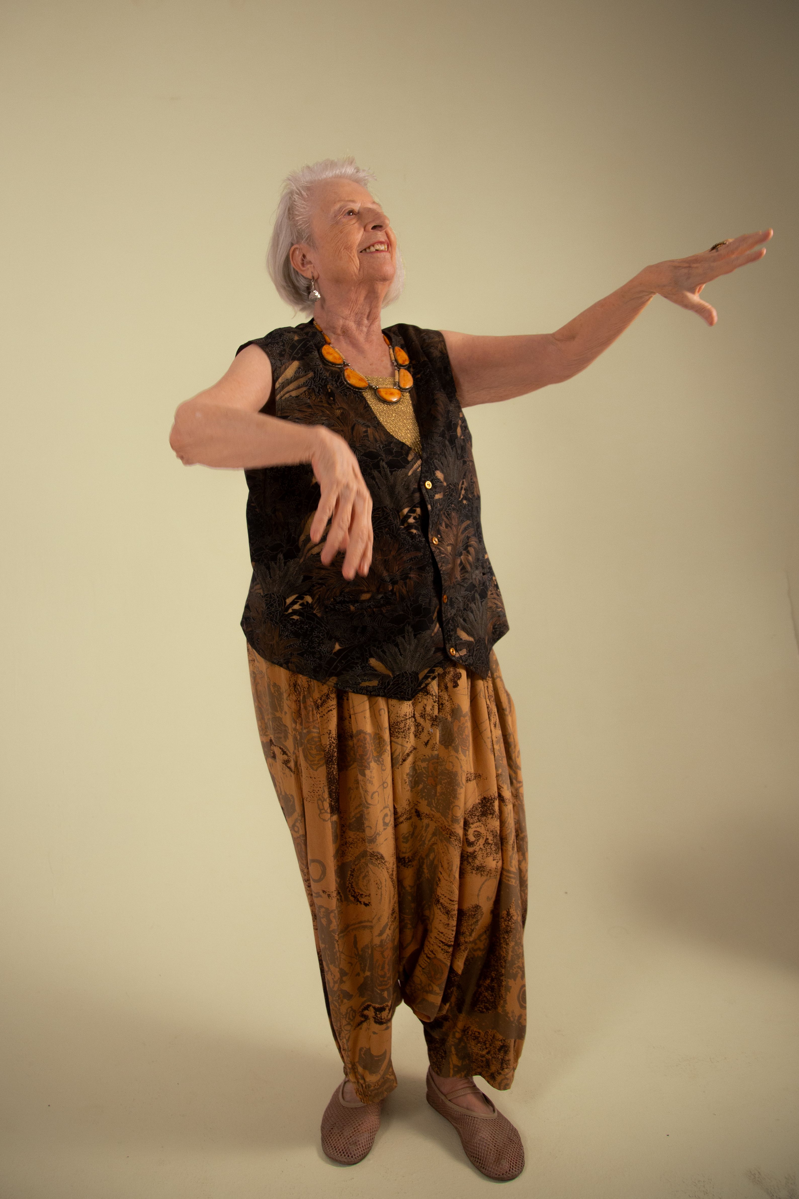 Charming senior woman in vintage clothing striking a graceful dance pose with a joyful expression.