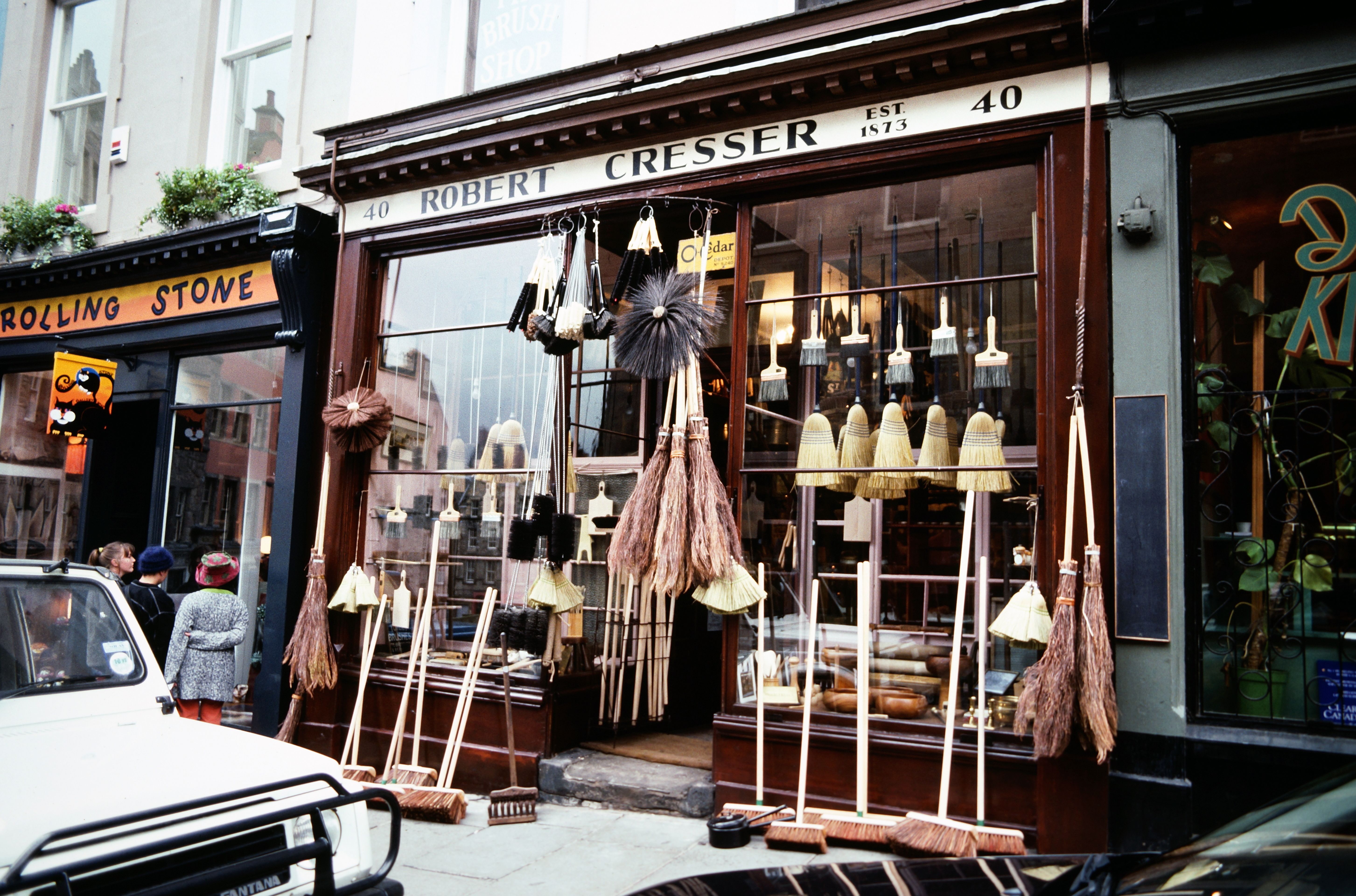 Charming broom shop in Edinburgh showcasing a variety of traditional brooms in the window.