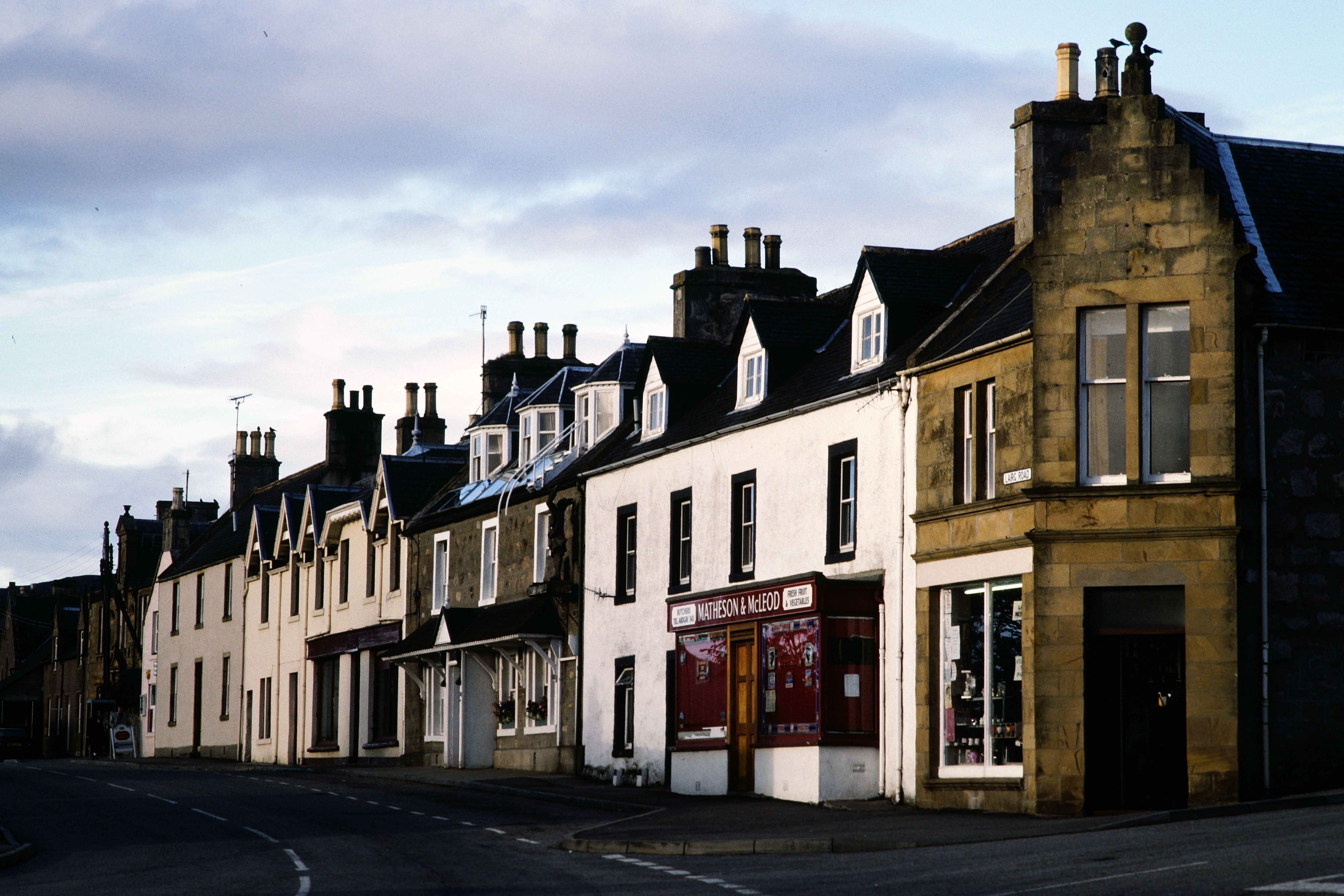 Quaint street in Scotland featuring traditional buildings under a moody evening sky.