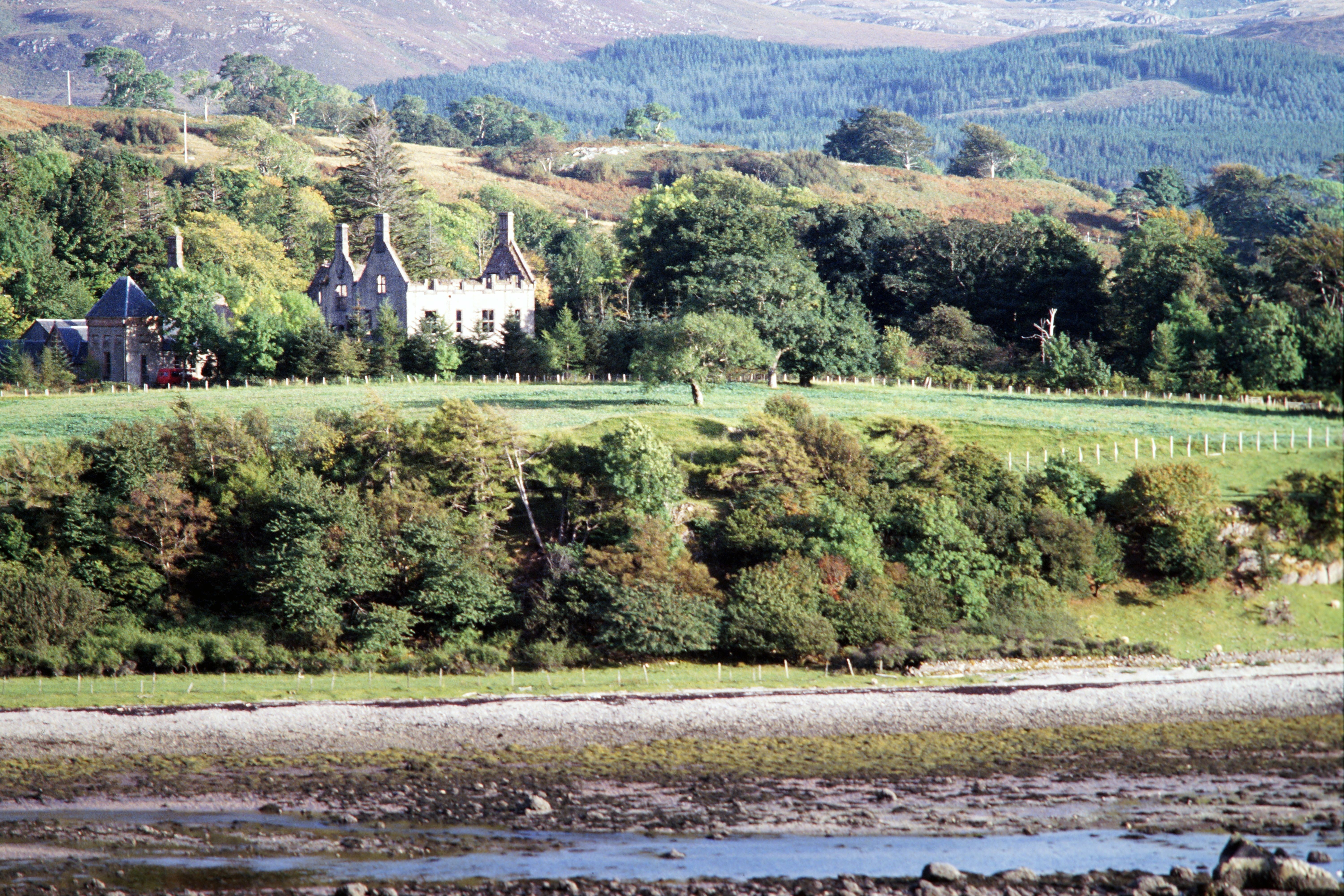 A picturesque view of a historic castle nestled in the lush Scottish Highlands landscape.