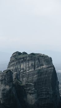 A striking view of the towering Meteora rock formation under a moody sky, Greece.