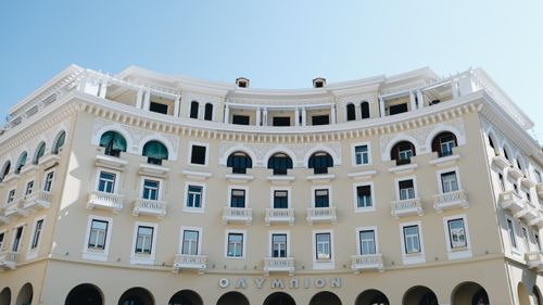 Free Beautiful neo-classical building facade with arched windows and decorative details in bright sunlight. Stock Photo