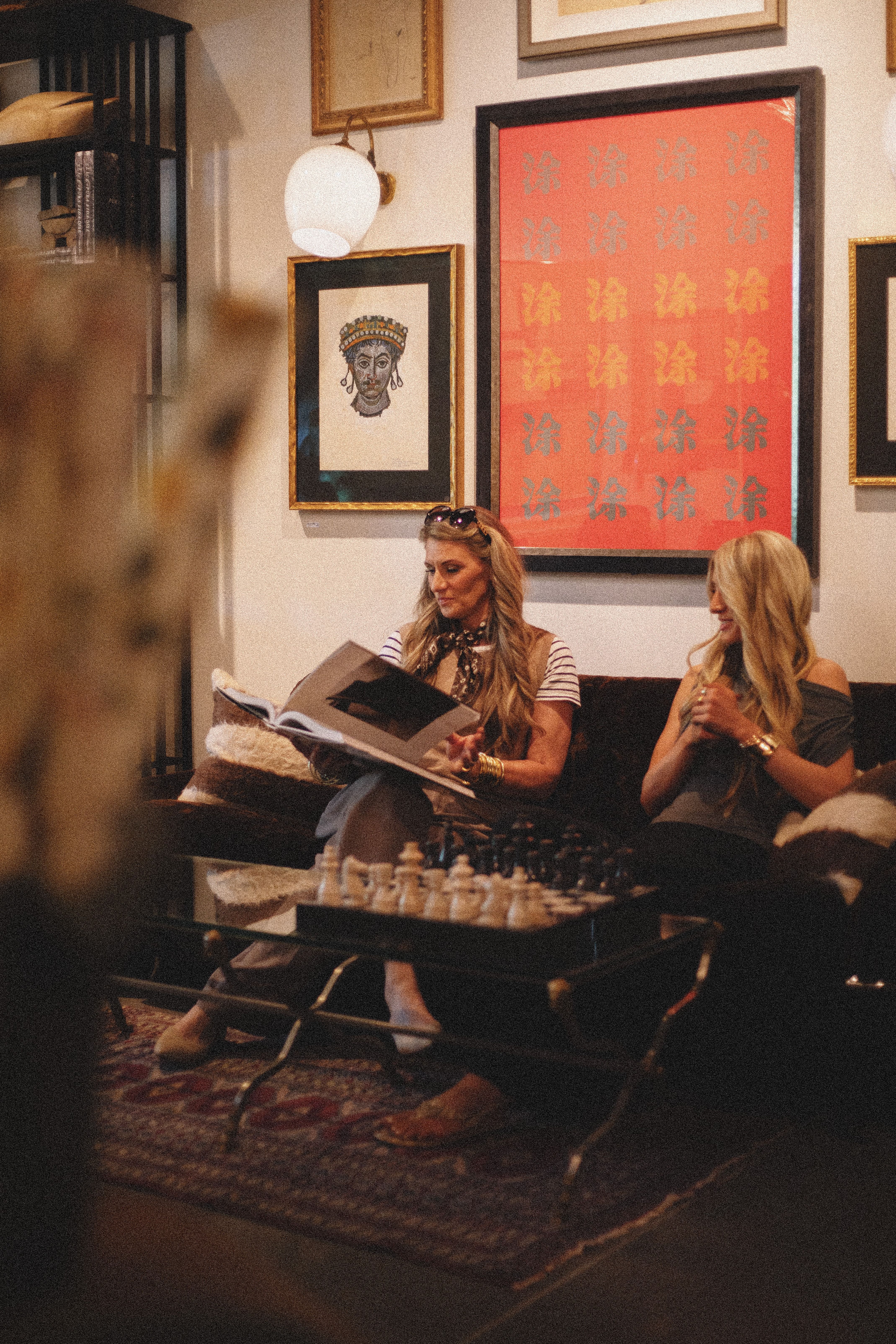 Stylish women in a vintage-inspired boutique filled with eclectic art and decor.