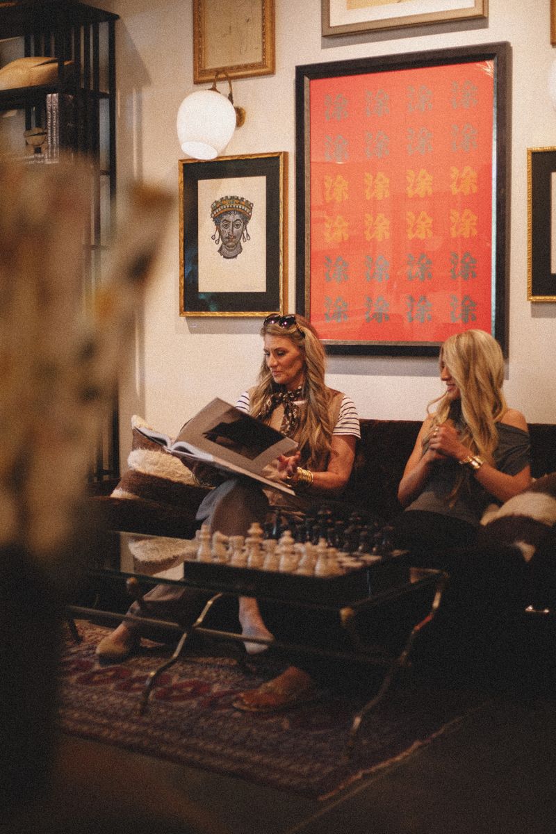 Stylish women in a vintage-inspired boutique filled with eclectic art and decor.