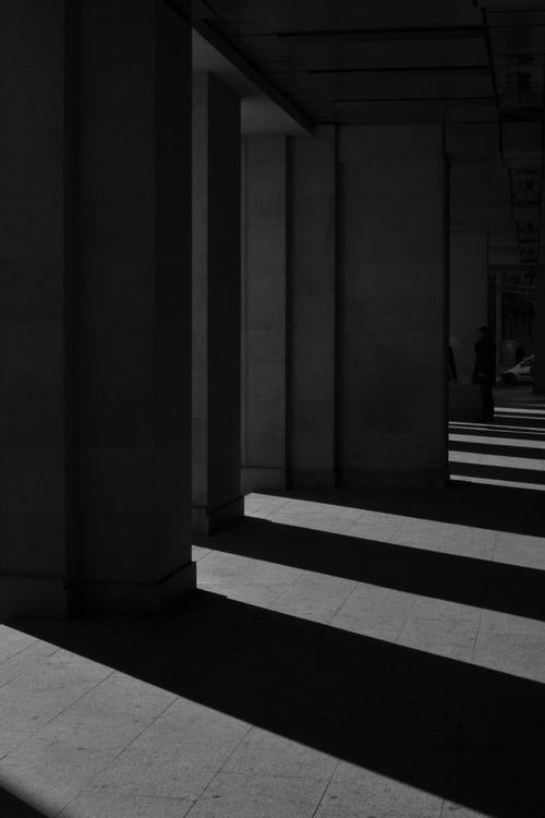 Free Dramatic interplay of light and shadow under architectural columns in black and white. Stock Photo