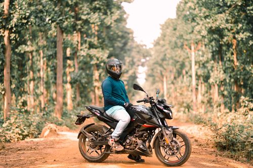 Free Man on a motorcycle in a scenic forest path, showcasing a sense of adventure Stock Photo