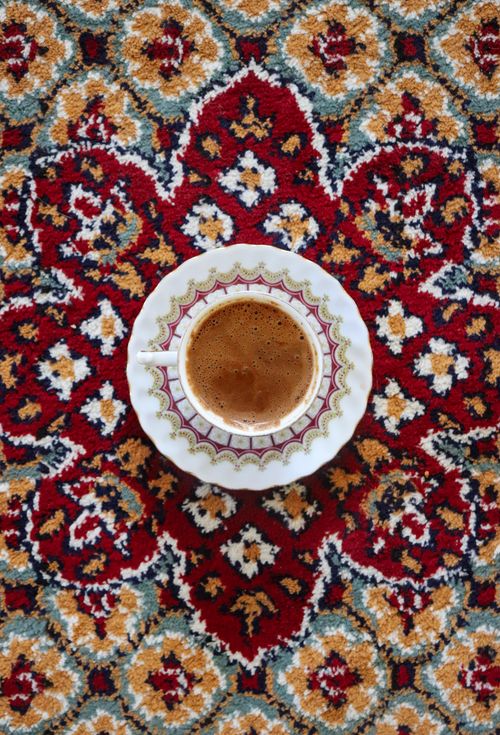 Free Top view of a cup of coffee placed on an intricately designed Persian carpet, showcasing cultural elegance. Stock Photo