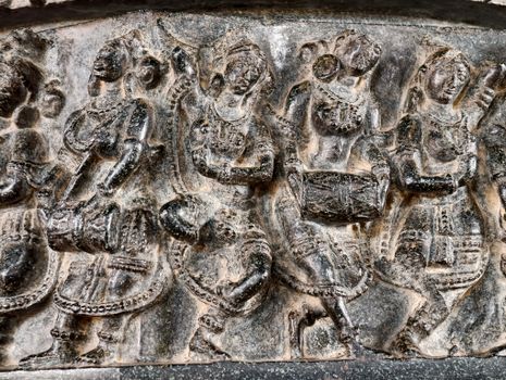 Intricate stone relief depicting traditional dancers in elegant attire, showcasing ancient artistry.