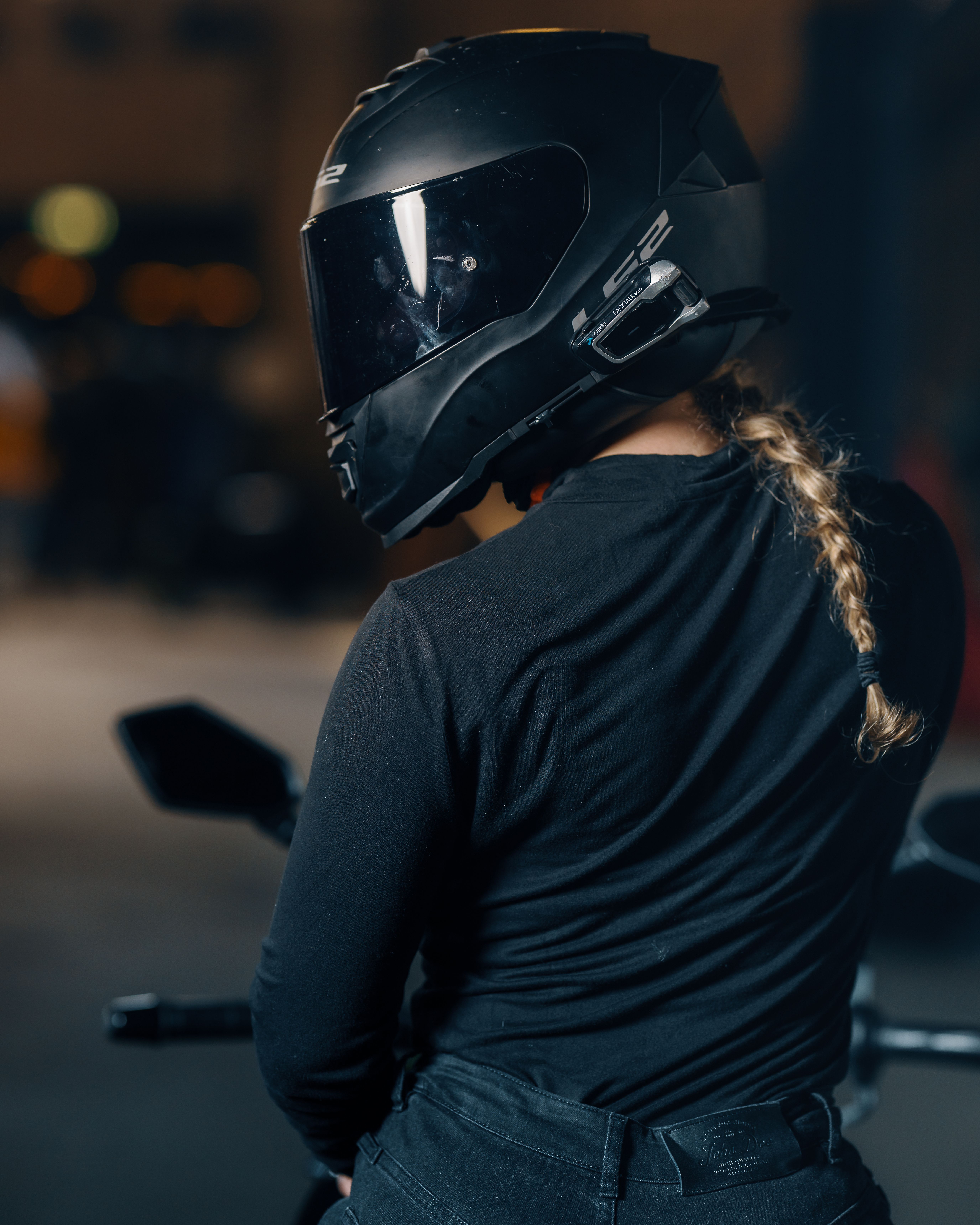 Casque moto noir équipé d'un intercom Bluetooth fixé sur le côté, motarde de nuit en ville