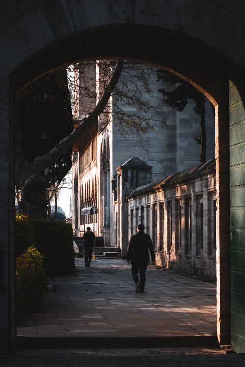 Free A serene view through a historic archway leading to a sunlit courtyard. Stock Photo