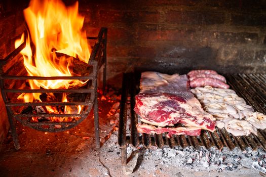 Close-up of an asado barbecue with a wood fire grill cooking various meats, showcasing traditional cooking techniques.