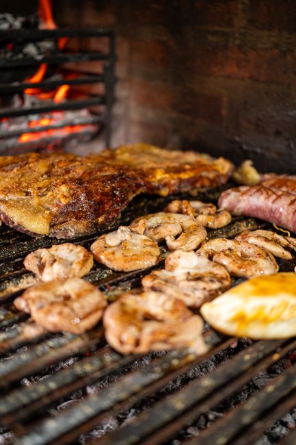 Fotomural Carne y salchichas a la parrilla chisporroteando en una barbacoa con llamas de fondo. Perfecto para barbacoas veraniegas.
