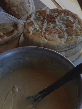 A stack of homemade flatbreads beside a bowl of dough, ready to bake, created in a cozy kitchen.