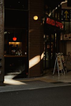 Warm light casts inside a cozy coffee shop entrance in a cityscape, capturing urban charm.