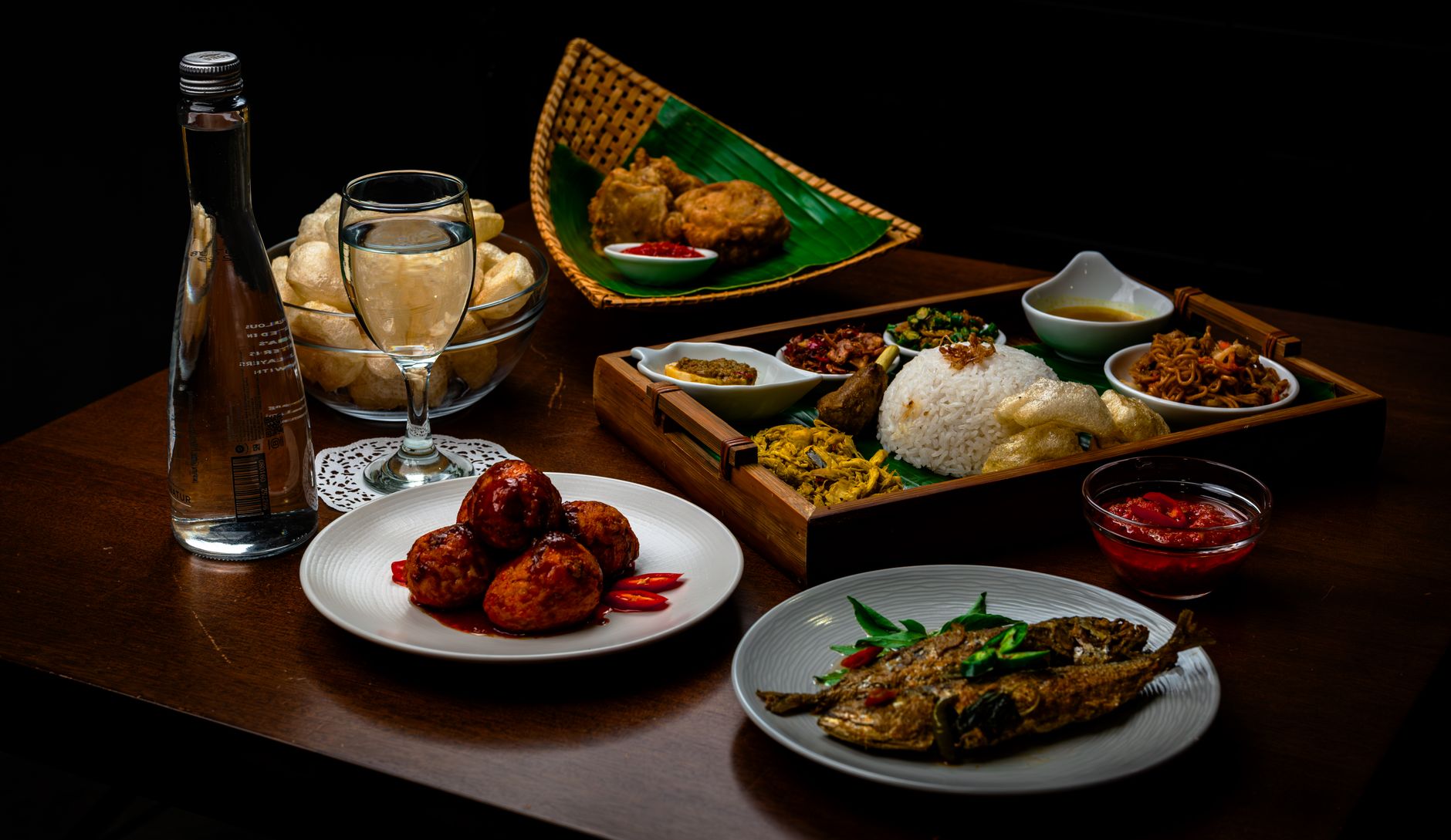 A vibrant and traditional Indonesian meal with various dishes served indoors on a wooden table.